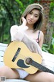 A woman sitting on a bench holding a guitar.