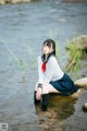 A woman in a school uniform sitting in the water.