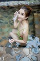 A woman in a green bathing suit sitting in a pool of water.