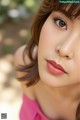 A close up of a woman's face with a pink dress.