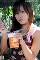 A woman holding a cup of ice cream and a fork.