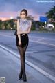 A woman standing on the side of a road at dusk.