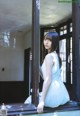 A woman in a white dress sitting on a window sill.